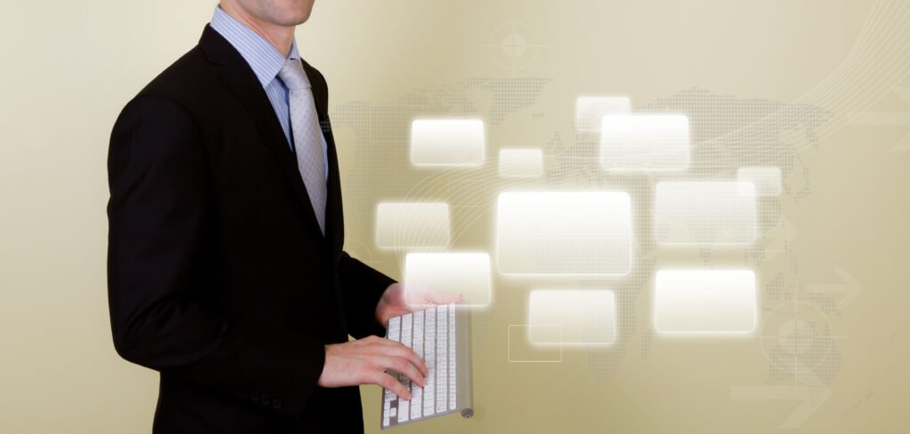 Un homme en costume tient un clavier d'ordinateur, debout devant un arrière-plan numérique avec des icônes rectangulaires éclairées.
