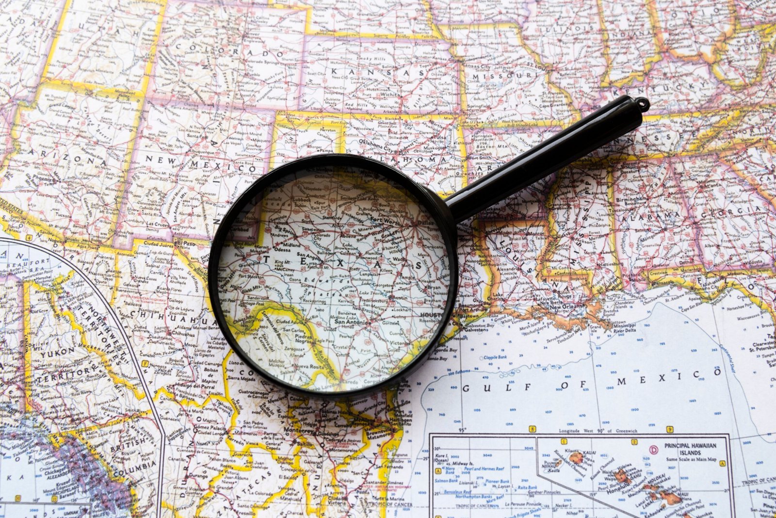 Une loupe placée sur une carte des États-Unis, se concentrant sur l'État du Texas et ses régions environnantes.
