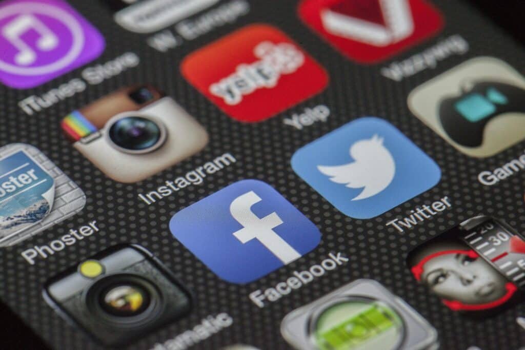 Gros plan d'un écran de smartphone affichant diverses icônes d'applications de médias sociaux, notamment Instagram, Yelp, Twitter et Facebook.